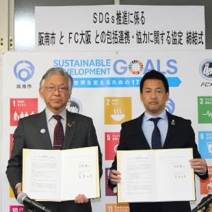 SDGs推進に係る阪南市とFC大阪との包括連携・協力に関する協定書を手にFC大阪スポーツクラブの吉澤会長と記念撮影する水野市長