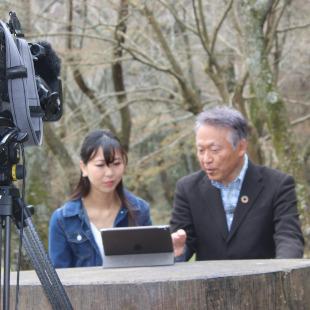 桜の園でのJcom番組収録にて、MC植田さんとベンチに座り、過去の出演映像を振り返る水野市長