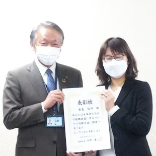 同志社大学政策学部の壬生裕子先生と功労者表彰状を手に記念写真を撮影する水野市長
