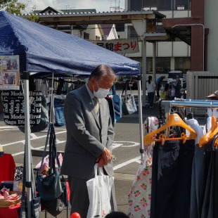 尾崎公民館まつりのフリーマーケットブースを見て回り出店者と会話する水野市長