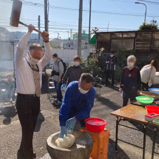 鳥取住民センターで開催されたおにぎり会の餅つき大会にて杵を担ぎ餅つきをする水野市長