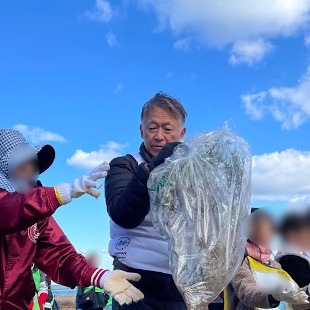 福島海岸での阪南セブン海の森活動にて海岸清掃活動に参加してゴミを運んでいる水野市長